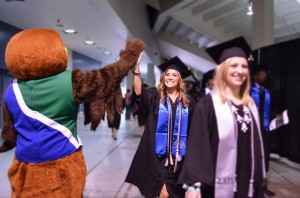 Graduating seniors being celebrated by Hunter the Hawk who is issuing high fives as they walk by. Image provided by UHCL Alumni Association. 