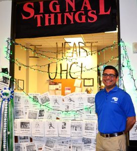 Patrick Cardenas, Assistant Director of Student Life for organizations and activities, poses in front of the winning window for best decorated window in the judged category. Photo by The Signal reporter Becky Shafter.