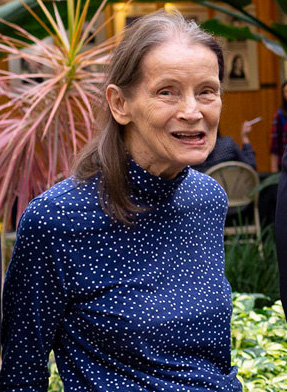 PHOTO: Professor Emerita of Literature Gretchen Mieszkowski took part in a UHCL charter faculty panel about the university's early history September 17, 2018. This panel was one of many activities in celebration of UHCL President Blake's Investiture Week. This image is cropped showing just Mieszkowski wearing a blue turtleneck with white polka dots. She is standing in front of the garden in Atrium I. Photo courtesy of UHCL Marketing and Communications.