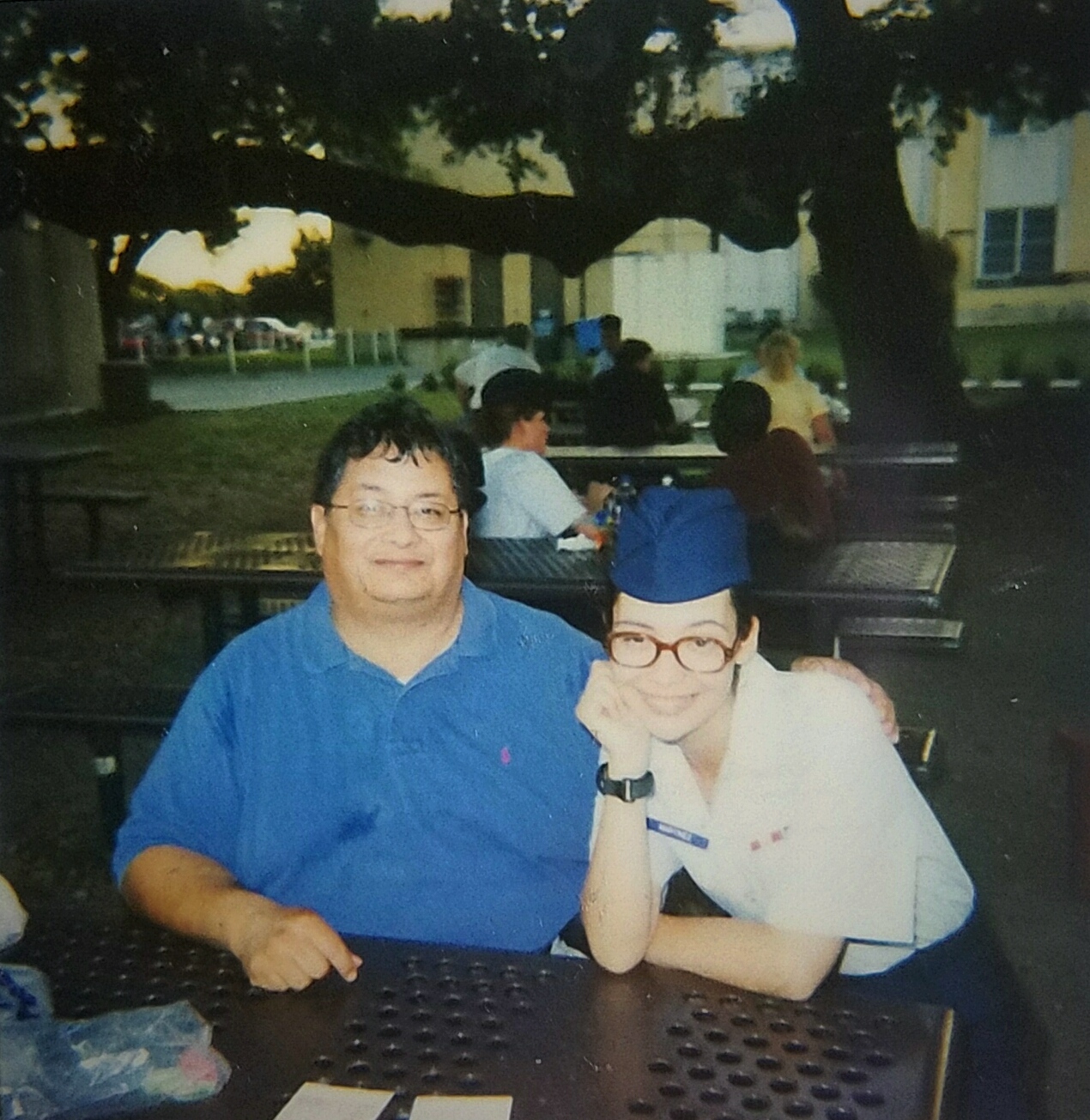 PHOTO: Photo of an older man and a young woman embracing each other while sitting at a table in courtyard. The older man is wearing a blue polo shirt, and the young woman is wearing Air Force blues. Photo courtesy of The Signal reporter Jennifer Martinez.