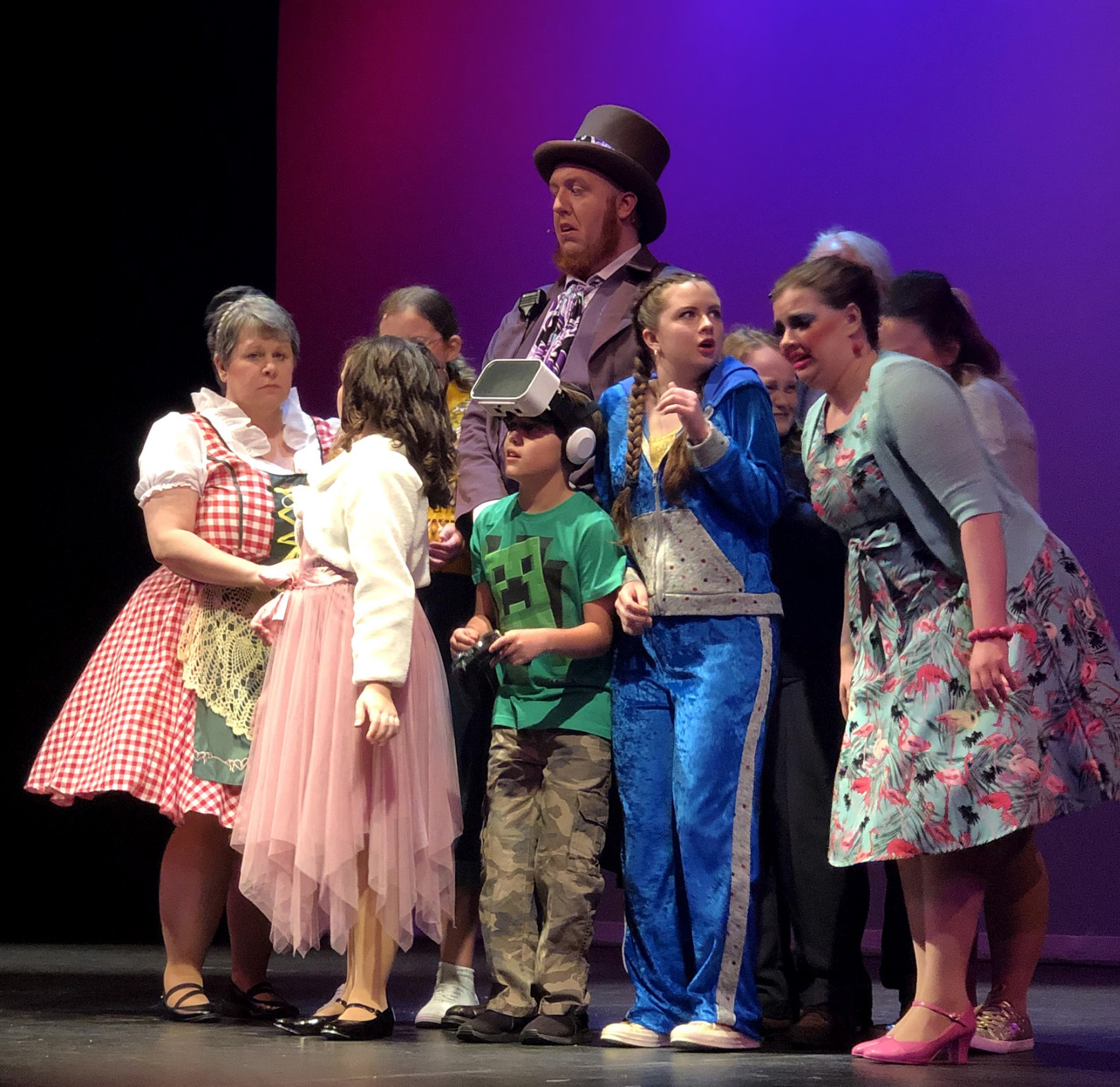 PHOTO: Willy Wonka remaining calm while golden ticket winners and their parents are anxious about seeing the chocolate factory. The guest are huddled around Wonka with him standing in the center. Photo by The Signal reporter Kathryn Wickenhofer.