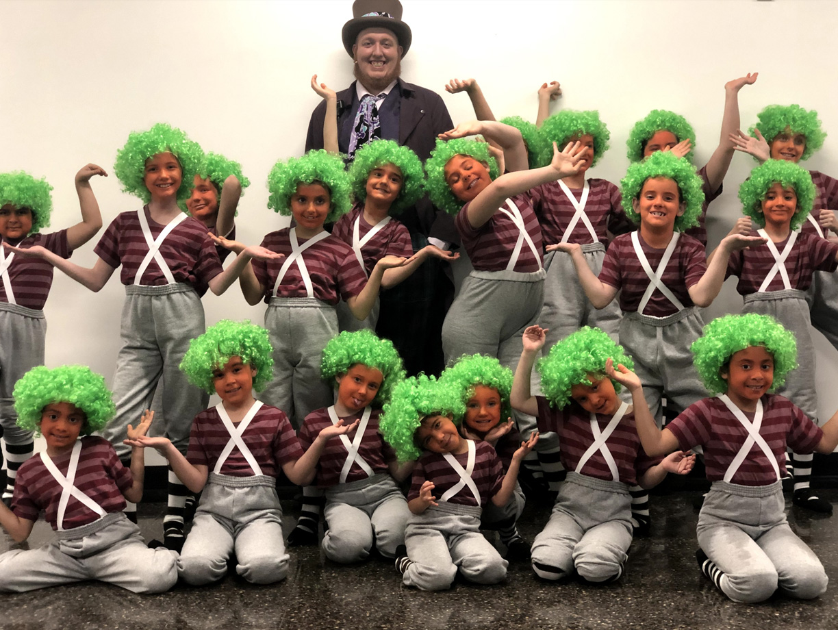 PHOTO: Willy Wonka surrounded by his Oompa-Loompas. The performance had eleven main Oompa-Loompas with older children and two sets of cast with younger tots that alternated shows. Eight set were called the "Gobstopper Cast" and nine were called the "Fudgewhipple Cast." Photo by The Signal reporter Kathryn Wickenhofer.